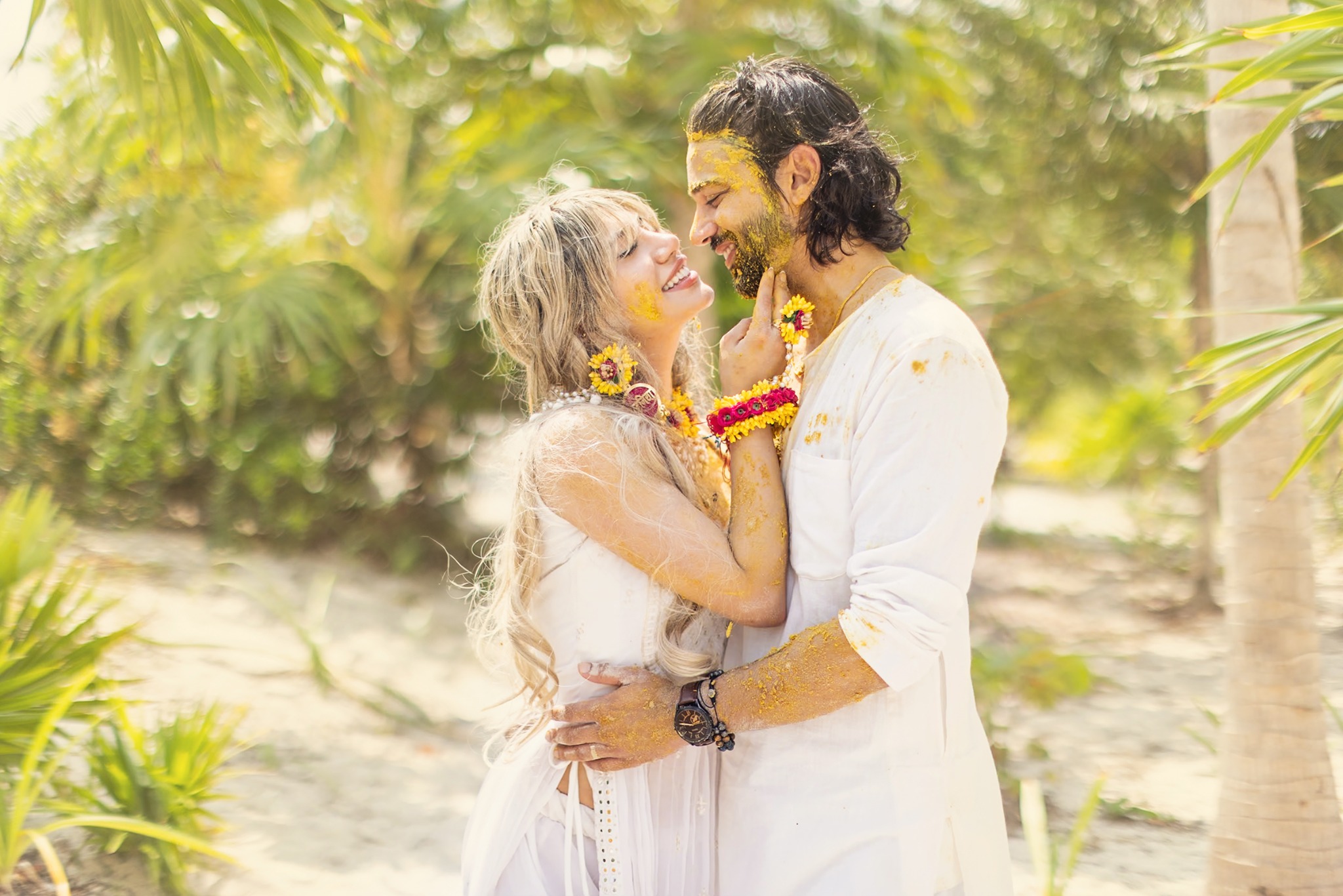Couple embracing during a haldi ceremony with yellow turmeric on their faces and clothing