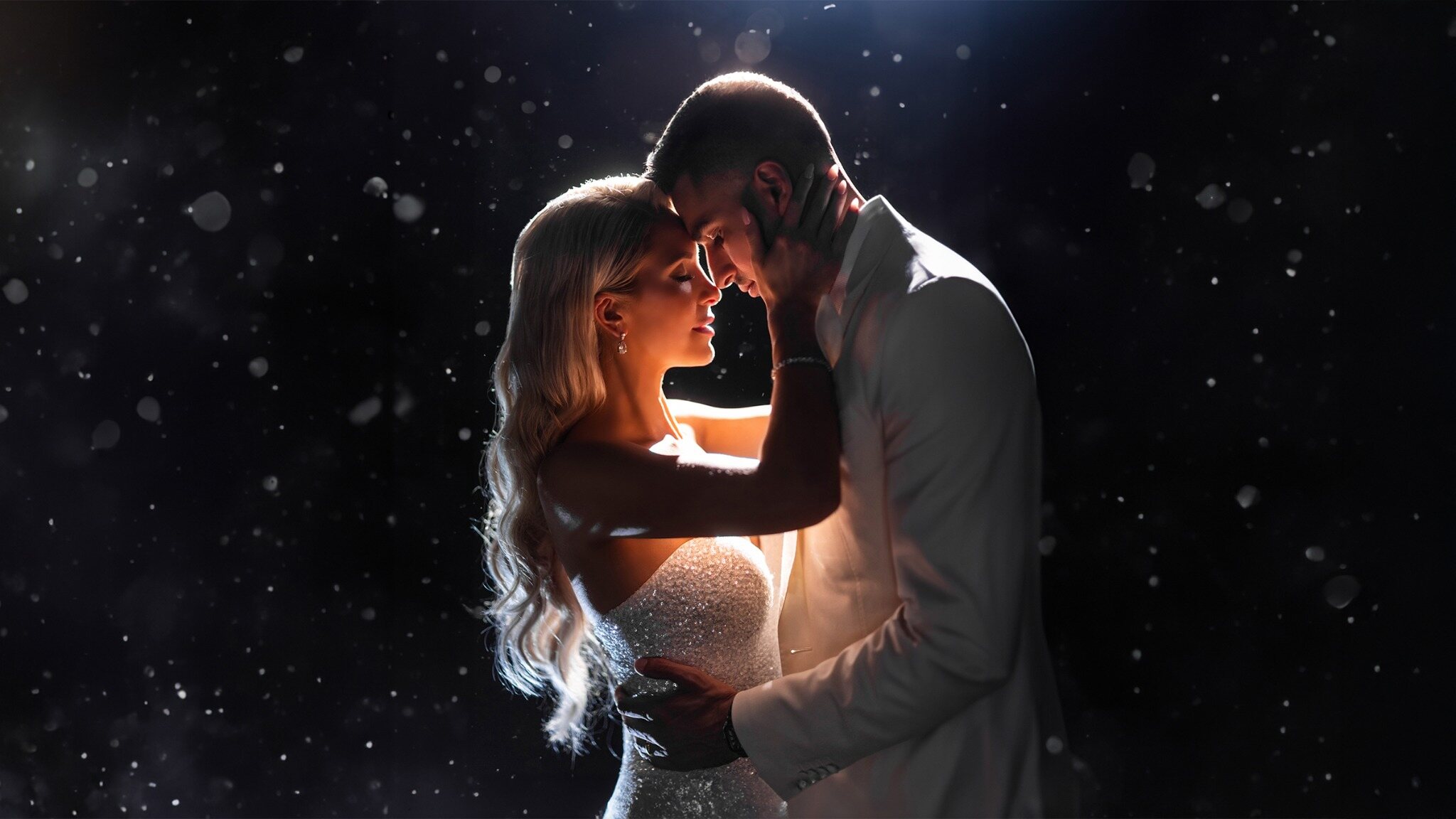 Couple sharing a dramatic portrait outdoors at night in falling snow