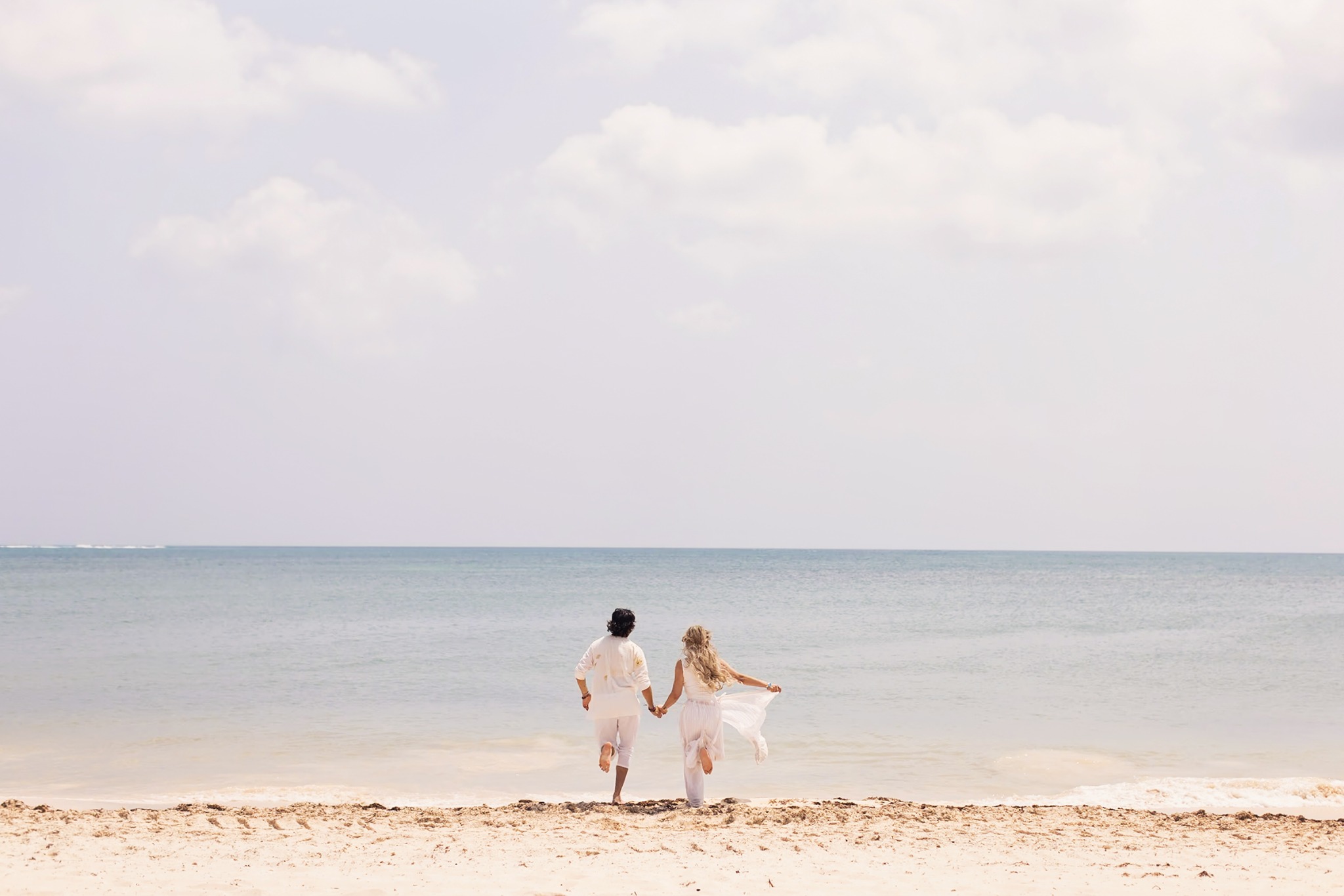 Couple walking hand in hand along a quiet tropical beach