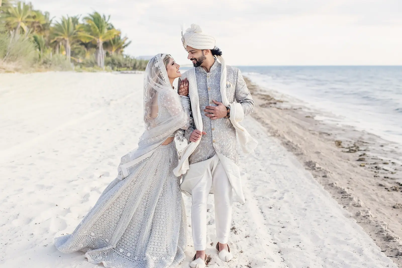 Tania and Saurabh walking together on the beach during their destination wedding